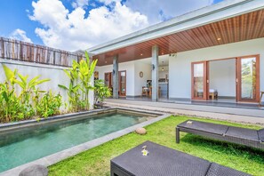 A modern outdoor pool area with a wooden pergola, a small garden with tropical plants, and a lounge chair. - VILLA TRATASAN CANGGU (Badung)