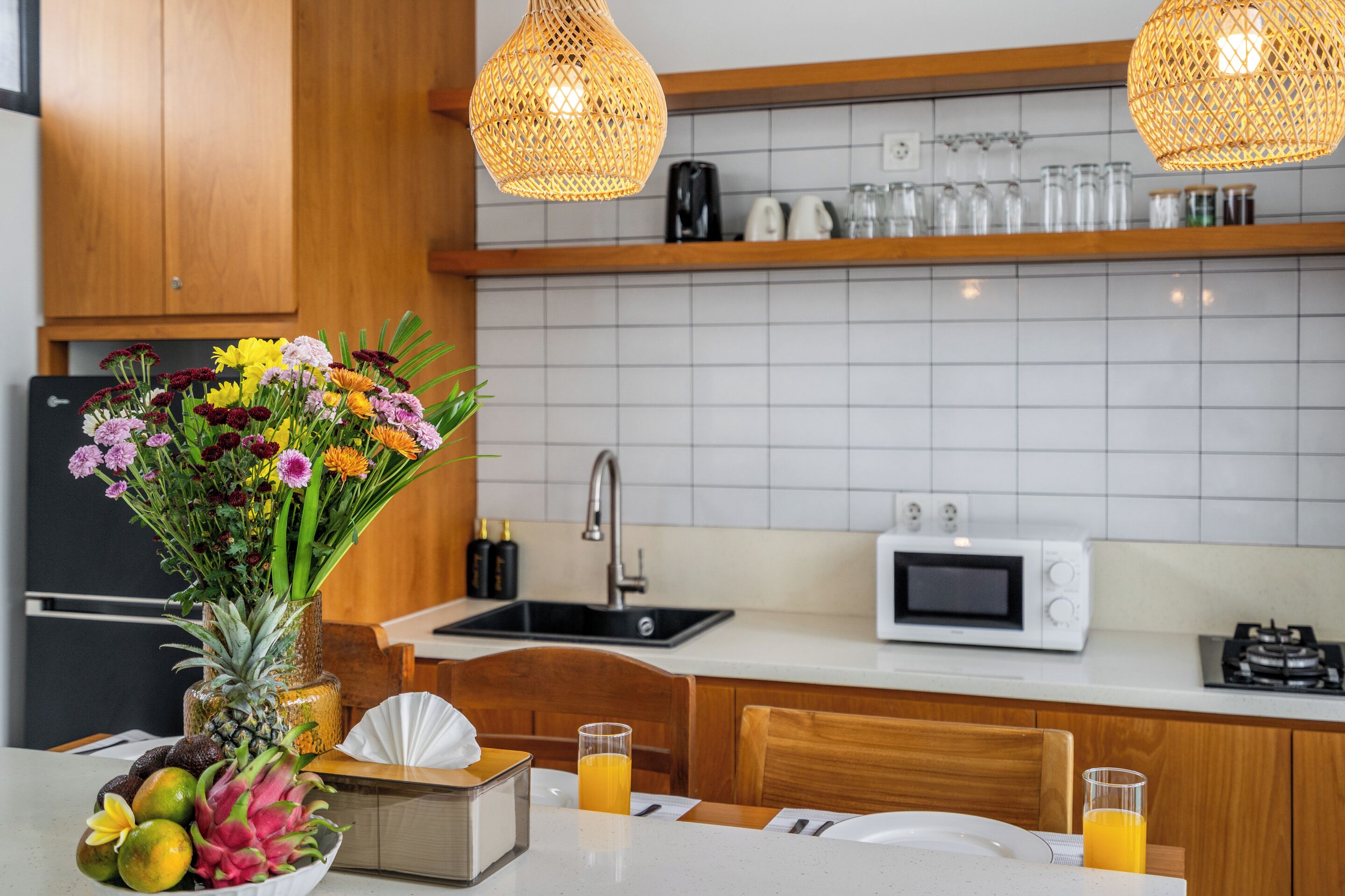 Una cocina moderna con encimera blanca, microondas, fregadero y armario de madera.