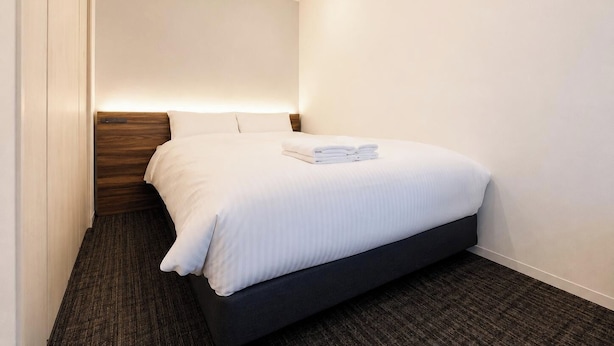 Een hotelkamer met een bed, een houten hoofdbord, een vloerbedekking en een plafondlamp.