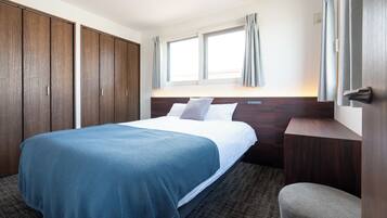 Habitación de hotel con cama, una silla, armario y ventana con cortinas.