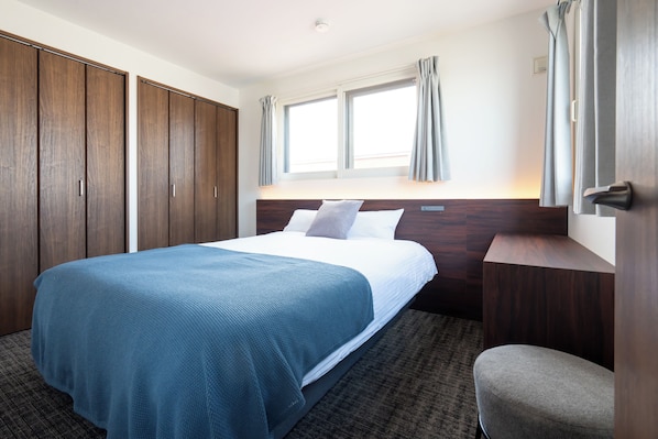 A hotel room with a bed, a chair, a wardrobe, and a window with curtains. - Hotel Luxe HIRAGISHI (Sapporo-shi)