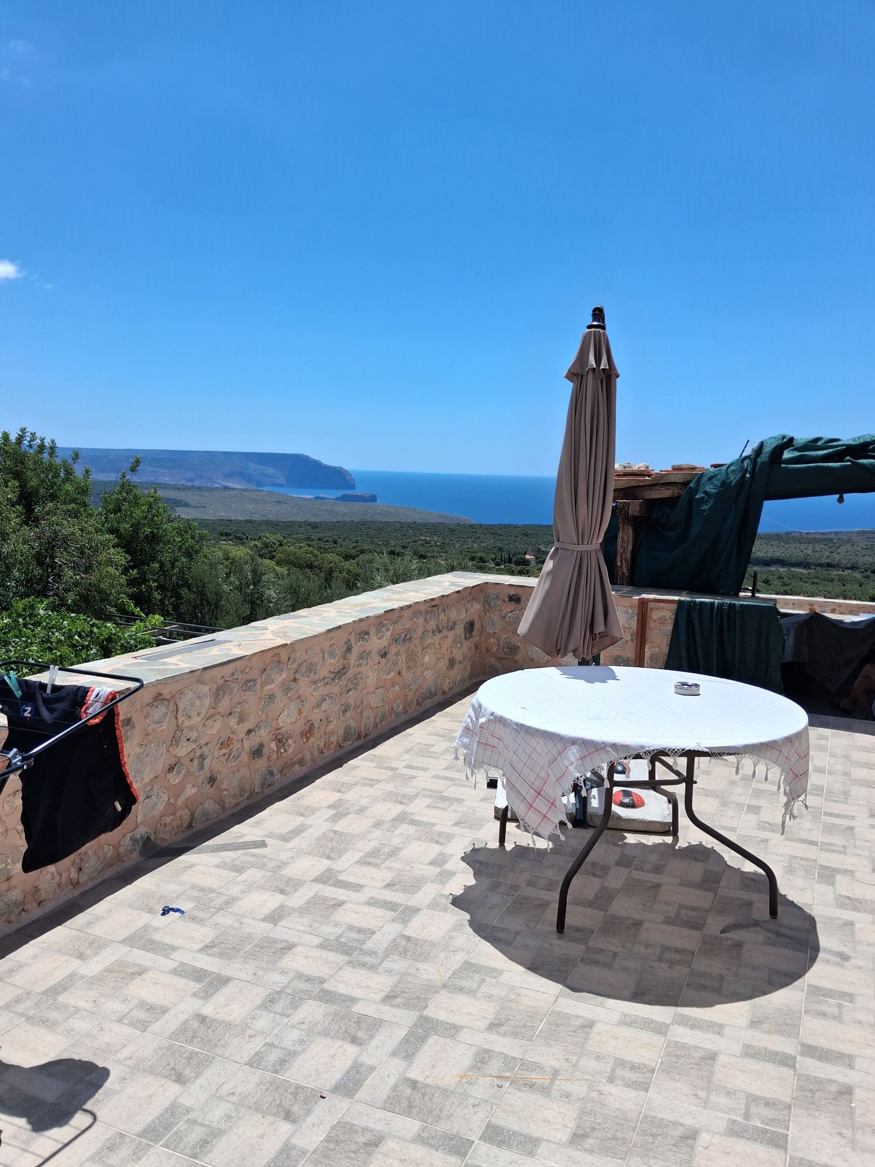 Una terrazza con tavolo e sedie, uno stendibiancheria e vista sul mare.
