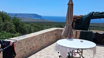 Una terrazza con tavolo e sedie, uno stendibiancheria e vista sul mare.