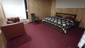 Un dormitorio con cama, sofá, sillón y pared de madera.