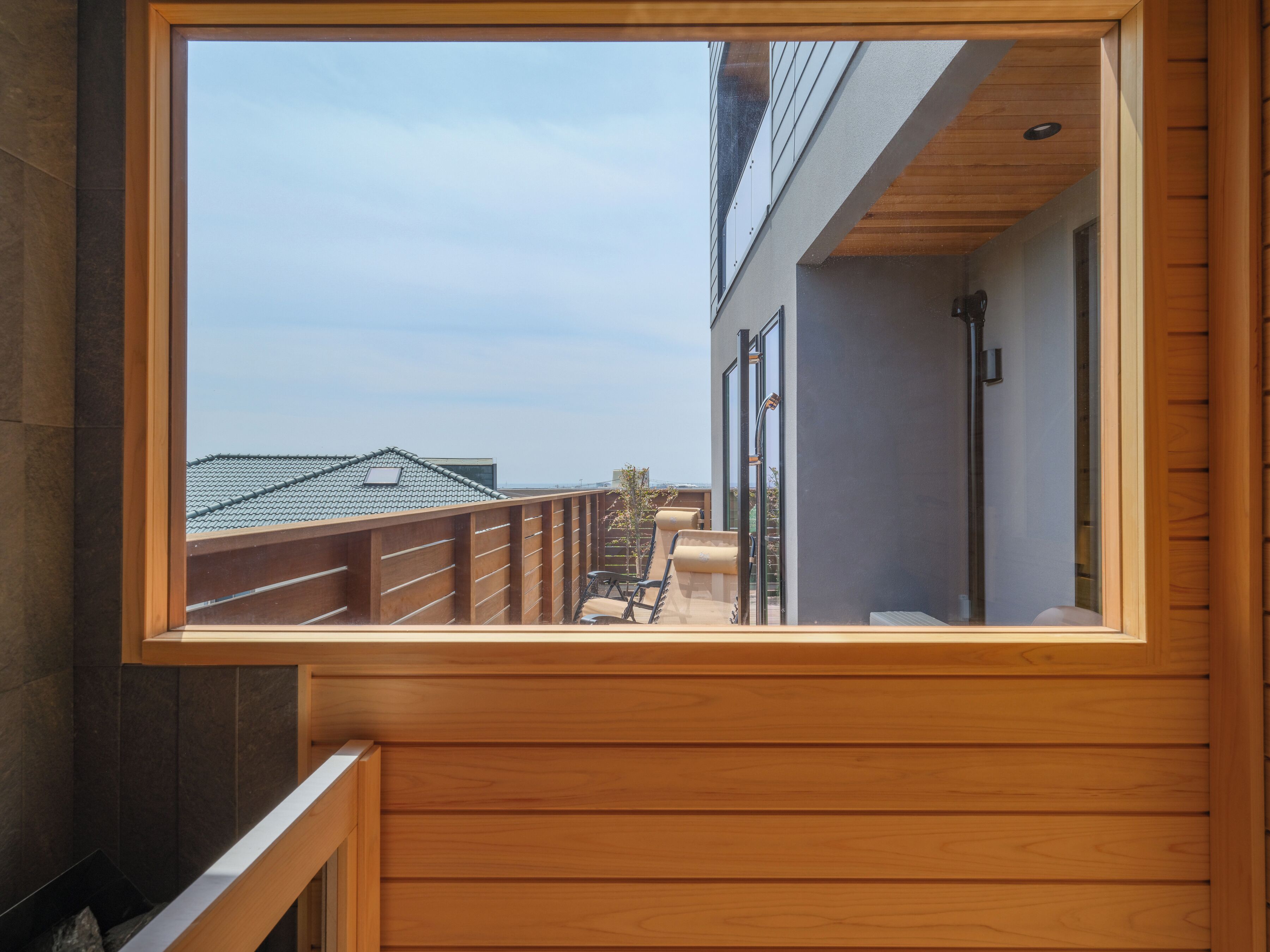 A balcony with a wooden railing, a view of buildings, and a clear sky.