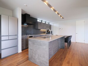 A modern kitchen with a central island, built-in appliances, and a tiled backsplash. - KAMAKURA VILLA SAUNA KOSHIGOE 5 (Koshigoe, Kamakura-shi)