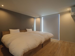 A bedroom with a large bed, wooden headboard, and a window with blinds. - KAMAKURA VILLA SAUNA KOSHIGOE 5 (Koshigoe, Kamakura-shi)