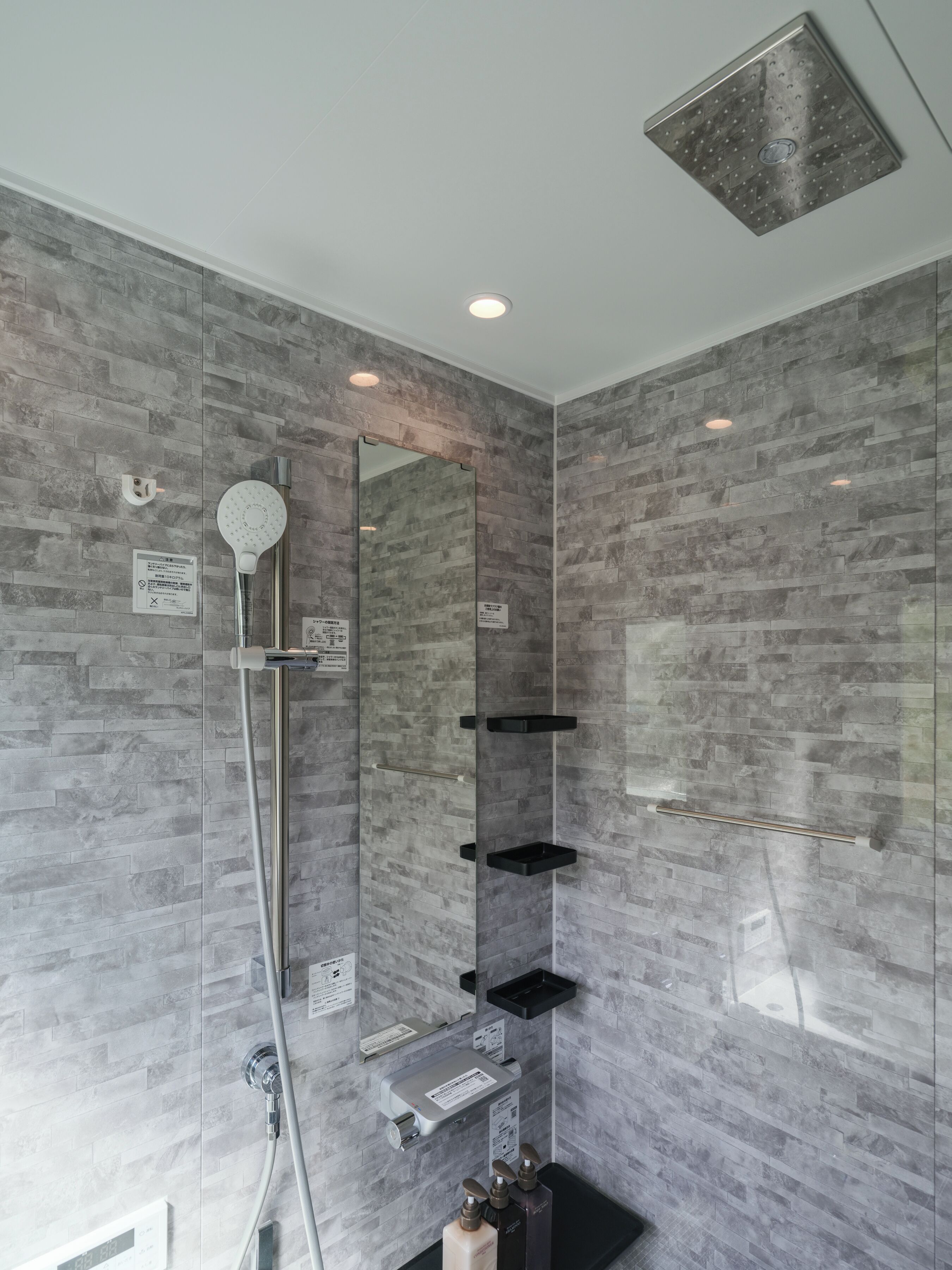Un baño moderno con ducha, espejo y estanterías empotradas.