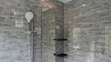 Un baño moderno con ducha, espejo y estanterías empotradas.