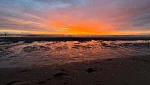 A beach with footprints and a sunset. - Cozy vacation home for two, close to the beach, the woods, and tulip fields (Callantsoog)