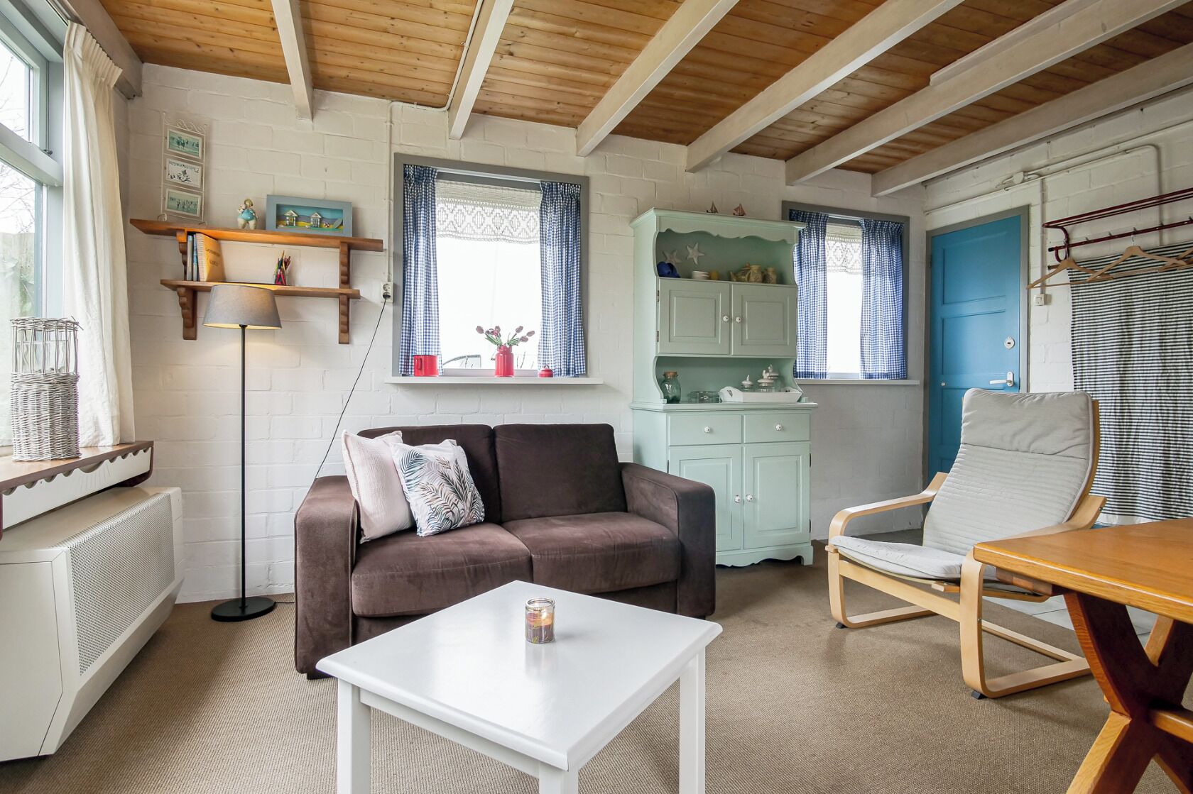 A cozy living room with a brown sofa, white coffee table, and a blue door.