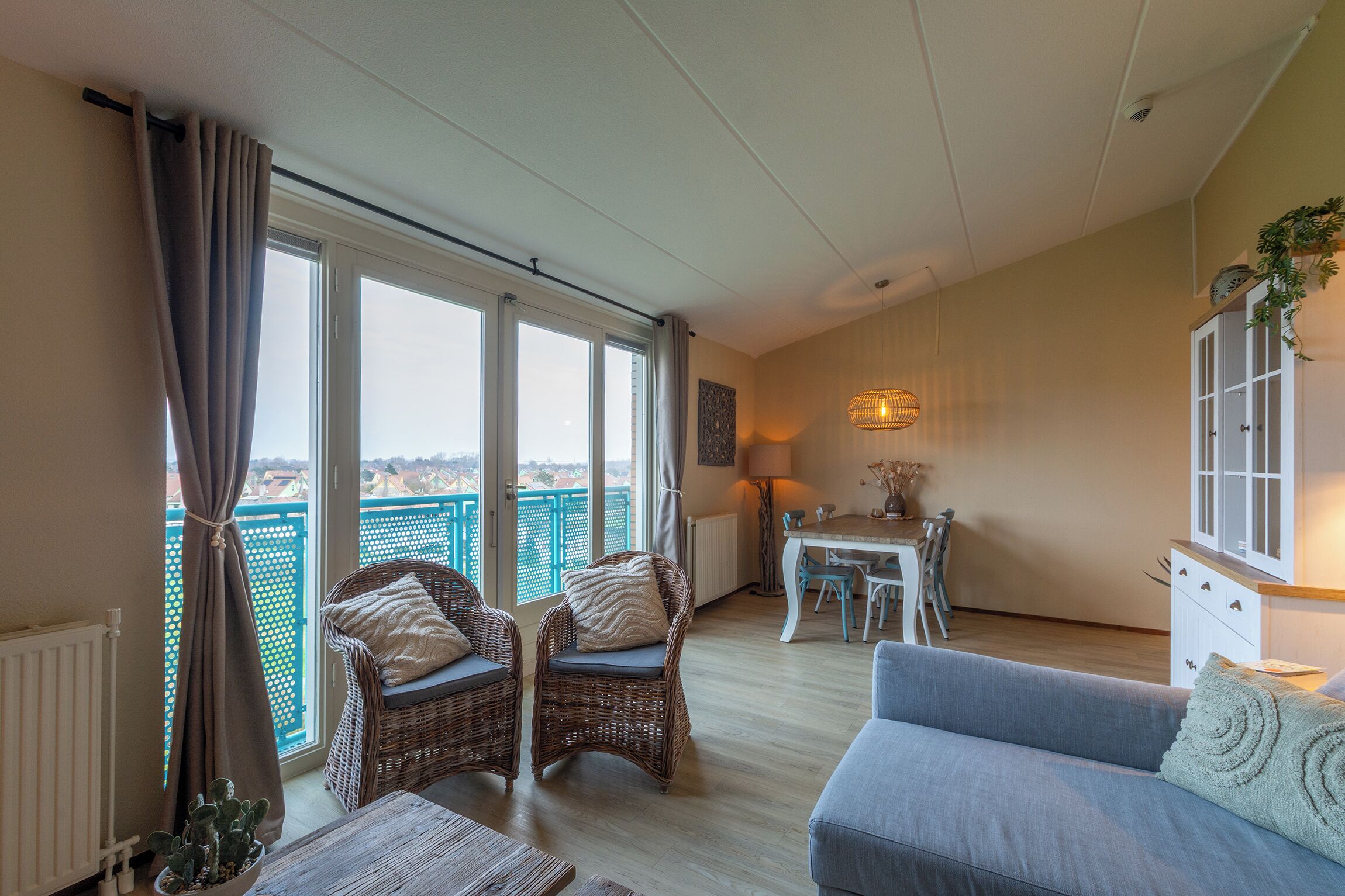 A balcony with wicker chairs, a dining table, and a sofa.