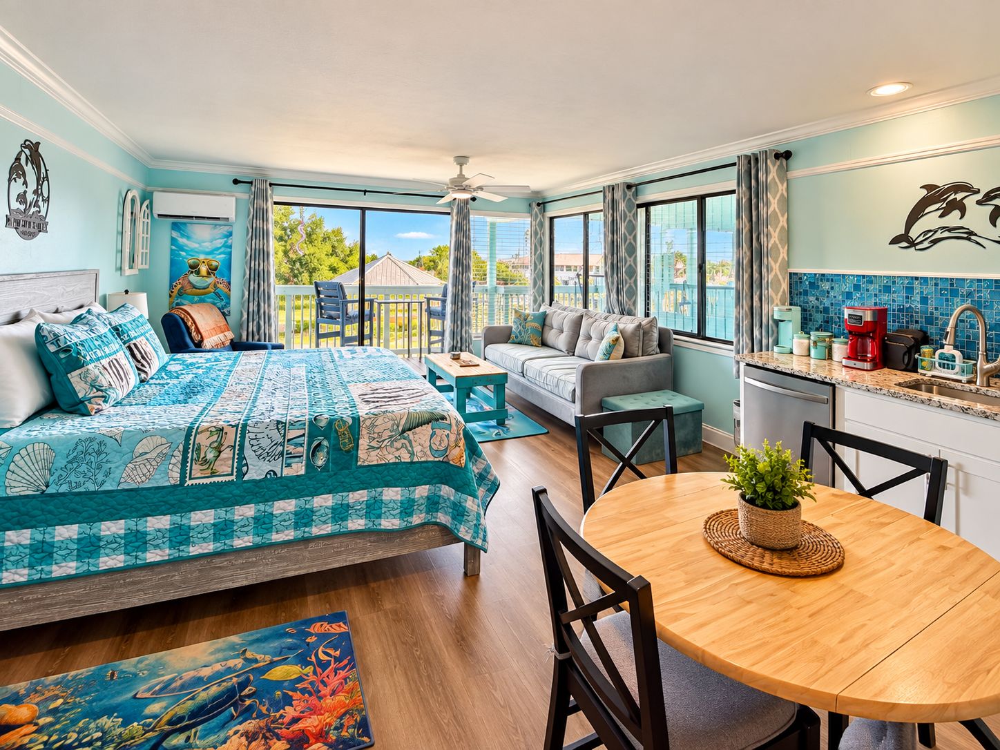 A room with a bed, a sofa, a dining table, and a kitchen area.
