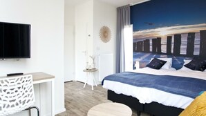 Un dormitorio con cama, televisión, una mesita y un adorno en la pared.