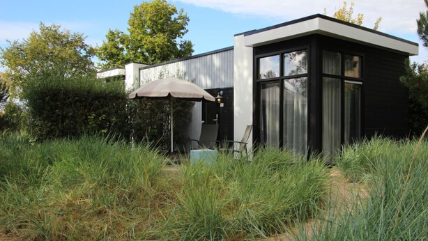 Un edificio moderno con un patio, una silla y una sombrilla.