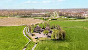 Een landelijk landschap met een groot groen veld, een kronkelende weg en een traditioneel huis met oprit.