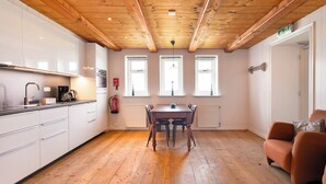 A kitchen with wooden beams, white cabinets, a dining table, and a sofa. - Spacious studio in an authentic Stolp farmhouse (Schagen)