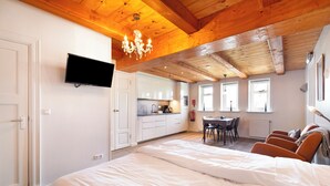 A bedroom with a large bed, a TV mounted on the wall, and a wooden ceiling. - Spacious studio in an authentic Stolp farmhouse (Schagen)