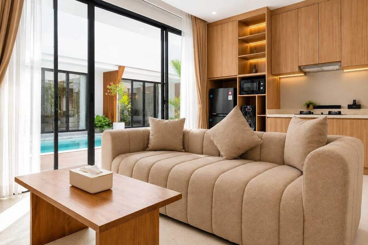 Una sala de estar moderna con un sofá, una mesa de centro y una cocina integrada con electrodomésticos.
