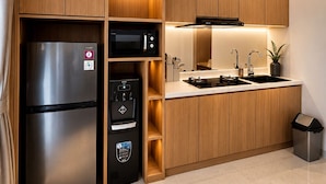 A modern kitchen with built-in appliances, a sink, and a trash bin. - HOTEL K Seminyak (Keroboken Kelod)