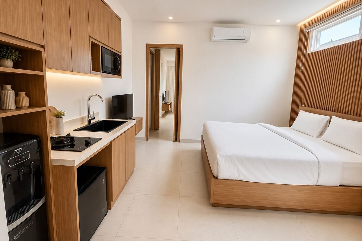 Une chambre moderne avec un lit en bois, un téléviseur encastré, un coin cuisine équipé d’un four à micro-ondes et d’un évier.