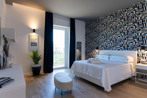 Un dormitorio moderno con una cama grande, una planta en maceta, un banco blanco y una pared con estampado.