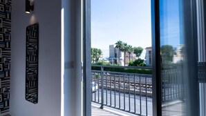 A modern interior with a large glass door leading to a balcony with a metal railing.