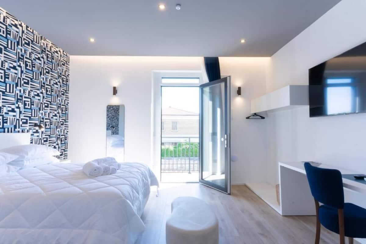Un dormitorio moderno con una cama, un escritorio y vistas a través de un ventanal.