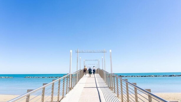 A pier leading to a beach with clear skies.