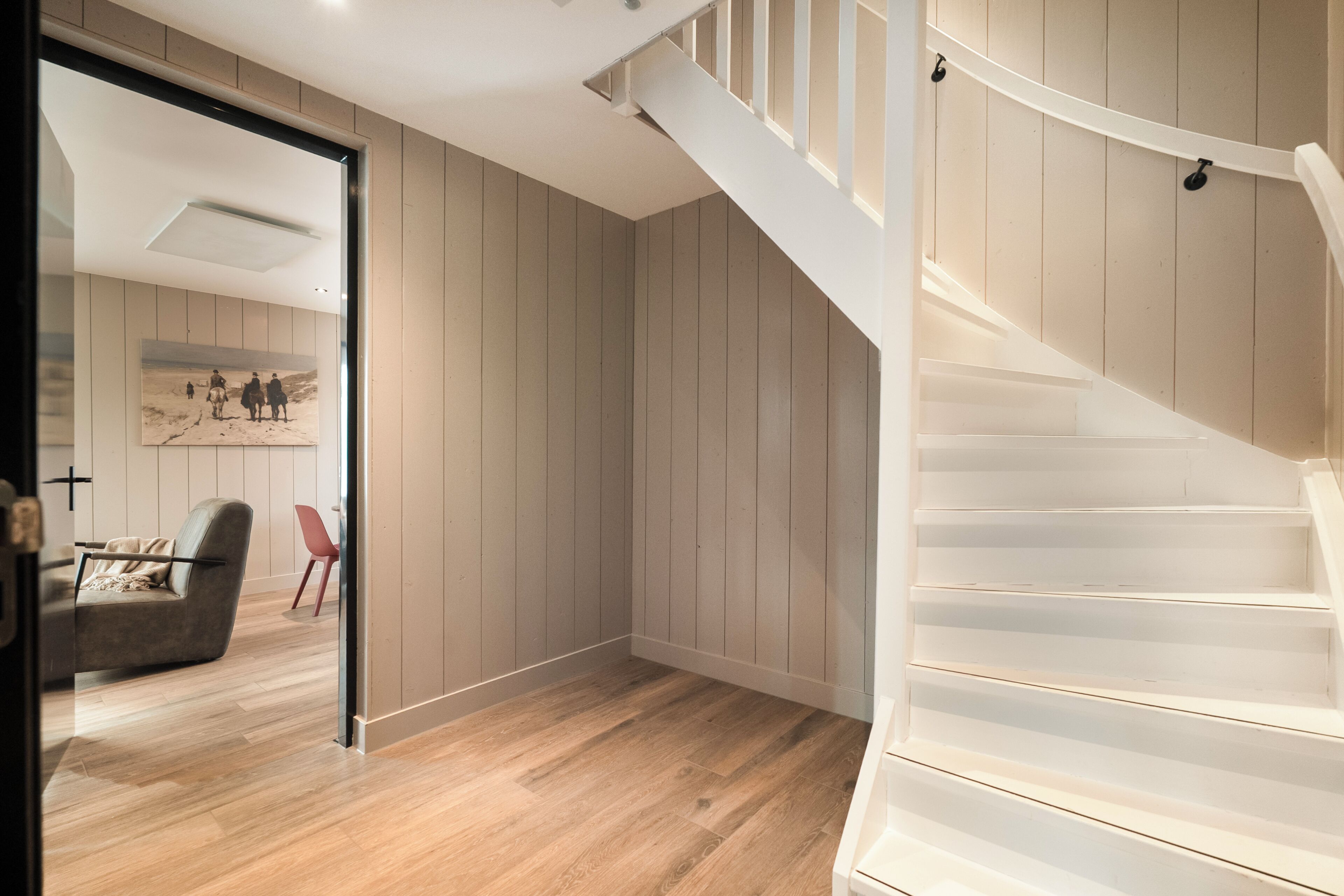 Ein modernes Interieur mit Holzboden, einer Treppe und einer Tür zu einem anderen Raum.