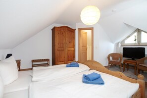A room with two beds, a wooden wardrobe, a television, and a window with a view. - Doppelhäuser am Strand auf Usedom in Ückeritz (Seebad Ueckeritz)