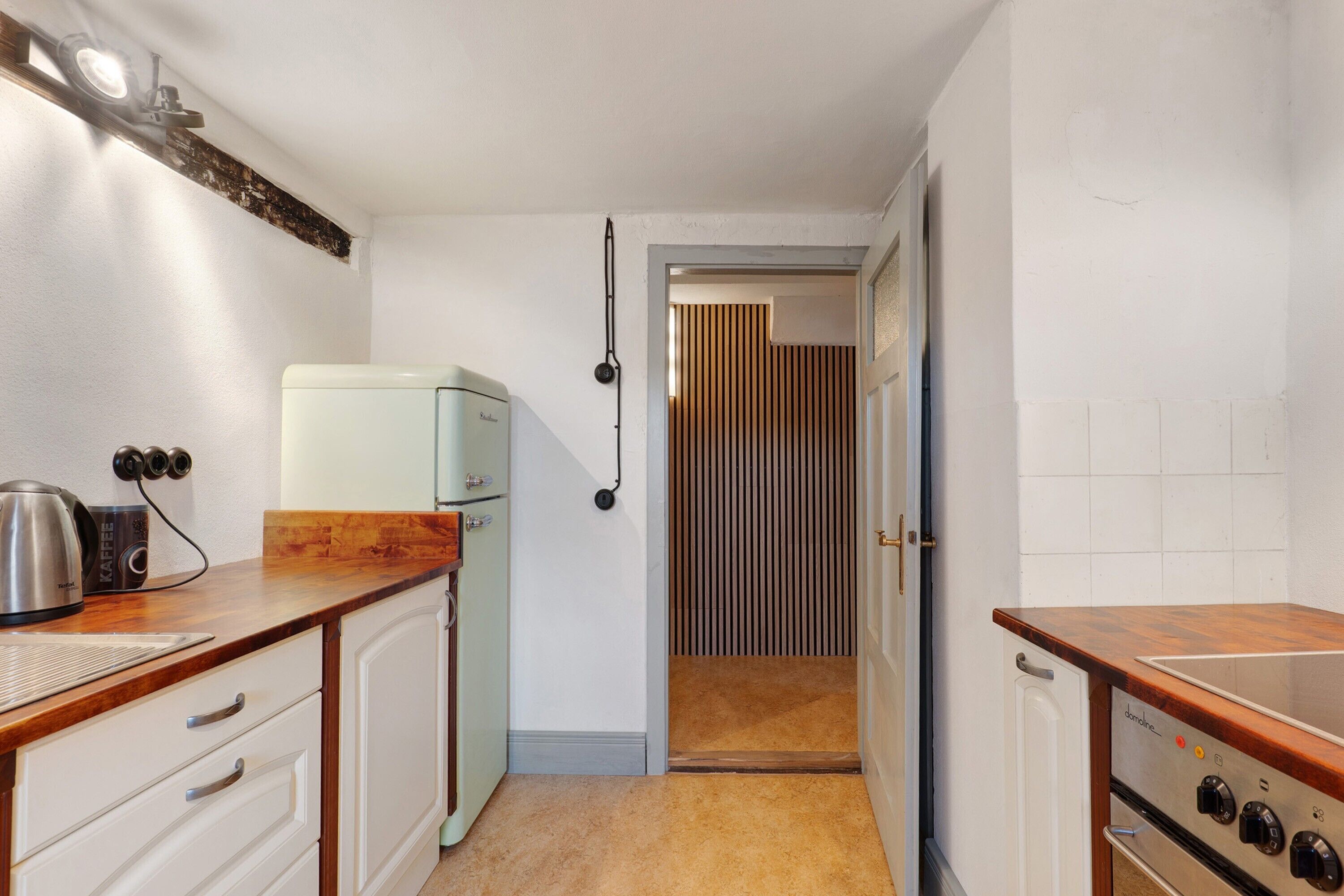 A compact kitchen with a white refrigerator, a coffee maker, and a stove.