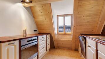 Una cucina compatta con pareti in legno, un piano cottura integrato e una finestra con vista su un balcone.