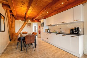 Een moderne keuken met witte kasten, een zwart aanrecht en een houten plafond.