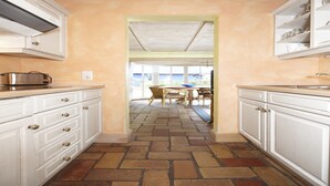 A kitchen with white cabinetry, a toaster, and a dining area with a table and chairs. - Doppelhhaus für 7 Personen am Strand in Ückeritz (Seebad Ueckeritz)