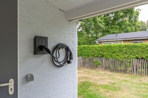 A white brick wall with a charging station and a door handle. - A beautiful, detached vacation bungalow in Park Duinland in Sint Maartenszee with a fully fenced-in yard! (Sint Maartensvlotbrug)