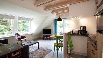 Ein Loft-Zimmer mit Essbereich, Küche und großem Fenster mit Blick auf Grünflächen.