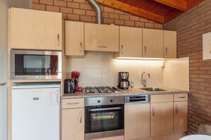 Eine kompakte Küche mit integriertem Mikrowellenherd, Backofen und Gasherd.