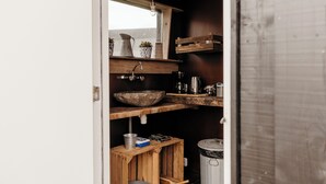 A compact kitchen with a wooden countertop, a sink, a hanging light fixture, and a trash can. - Unique accommodation (Callantsoog)