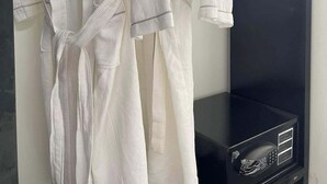 A white robe hanging on a black wall-mounted rack.