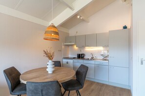 Eine moderne Küche mit weißen Schränken, einem runden Holztisch und grauen Stühlen.