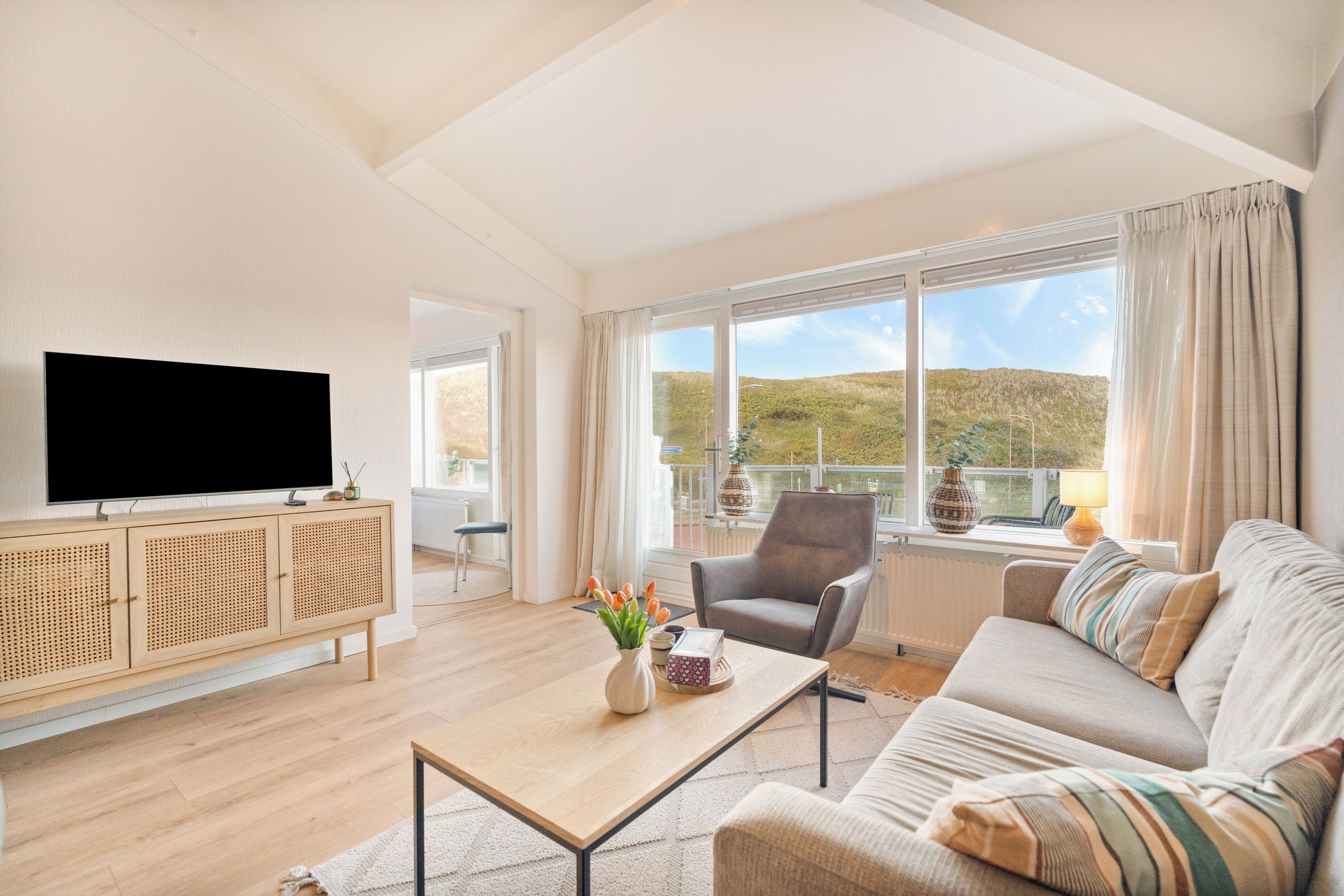 Una sala de estar moderna con una televisión de pantalla plana, un sofá, un sillón y una mesa de centro.