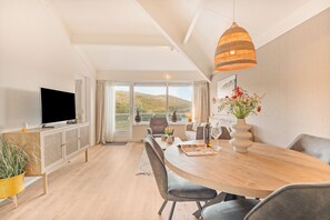 Una sala de estar moderna con una televisión de pantalla plana, una mesa de comedor y sillas.