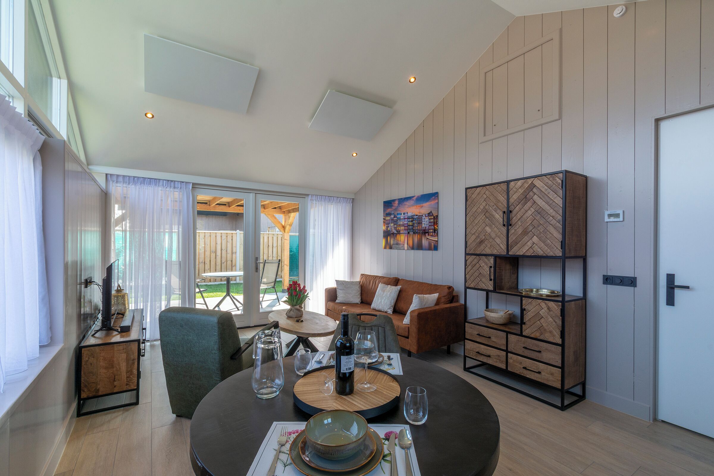 A modern living room with a round dining table, a sofa, a TV, and a wooden cabinet.