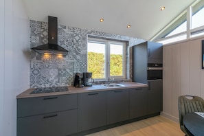 A modern kitchen with patterned backsplash, a window, and built-in appliances. - Luxury Wellness Villa for 2 People (Julianadorp)