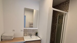 A bathroom with a sink, mirror, towel rack, and patterned wall tiles. - L'Authentique Aparthotel: Charming Accommodations in Brive (Brive-la-Gaillarde)