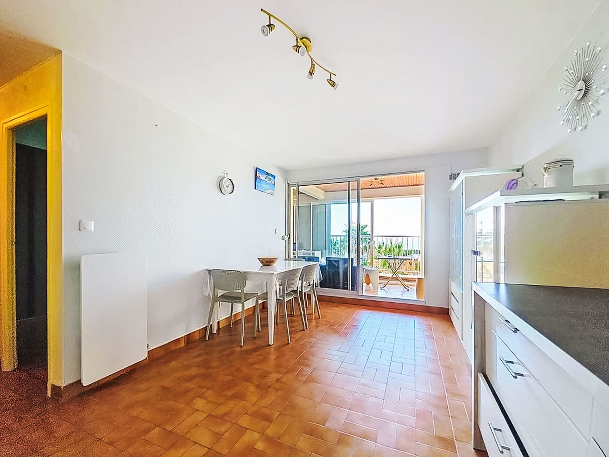 Una cocina con comedor, un balcón con vistas y una lámpara de techo.