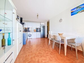 A modern kitchen with white cabinets, a washing machine, and a dining area with a table and chairs. - L'Acropole by Interhome (Cap d'Agde)