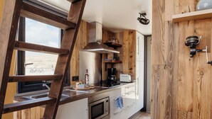 Een keuken met houten inrichting, een roestvrijstalen afzuigkap, een inbouwoven en een raam met uitzicht.
