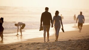 Eine Strandansicht mit Menschen, die am Ufer entlanggehen.